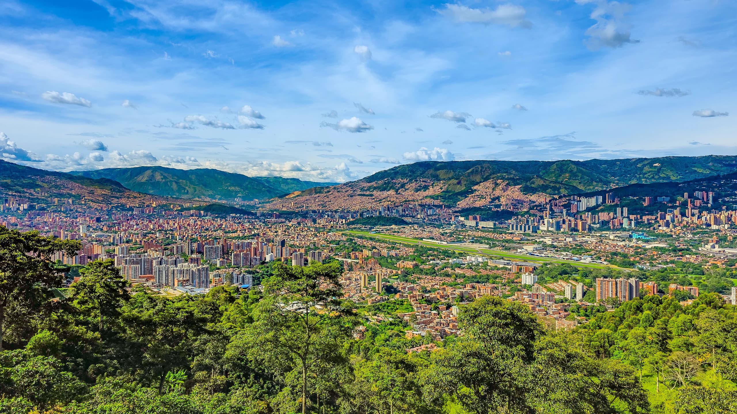 Vista panorámica de Medellín rodeada de montañas y vegetación.